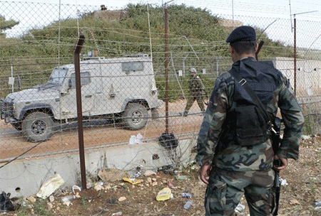 un soldado libanés observa una patrulla israelí al otro lado de la valla