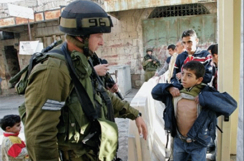 soldado israelí registra a un niño palestino