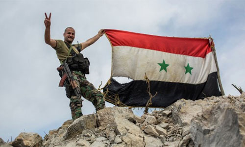 soldado sirio iza la bandera nacional en Alepo