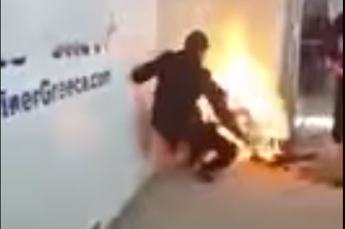 un agente intenta ayudar al refugiado ya incendiado