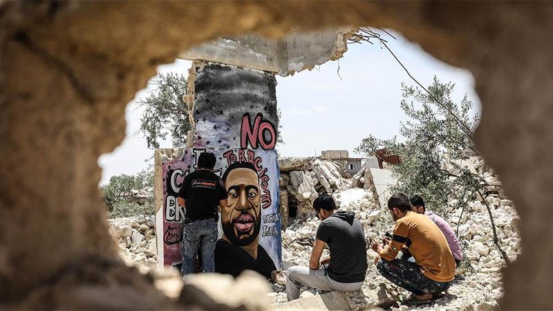 Un artista sirio dibuja un retrato de George Floyd sobre un muro en ruinas