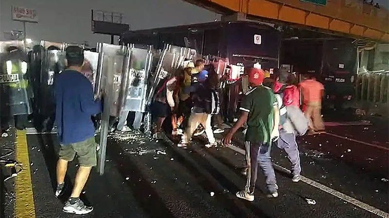 Migrantes se enfrentan a polic&iacute;as por el cierre de la autopista de M&eacute;xico-Puebla