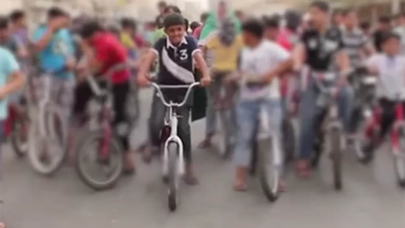 Murtaja Qureiris protesta en bicicleta junto a un grupo de niños