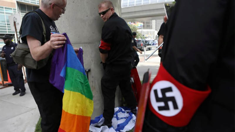 un miembro del grupo nazi orina sobre una bandera israelí